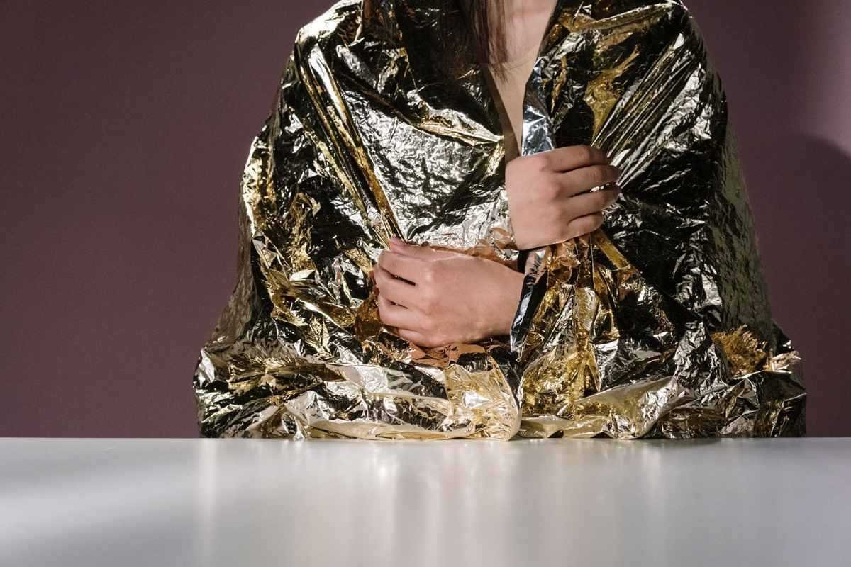 Une personne enveloppée dans une couverture en papier aluminium, assise Une personne enveloppée dans une couverture en papier aluminium, assise